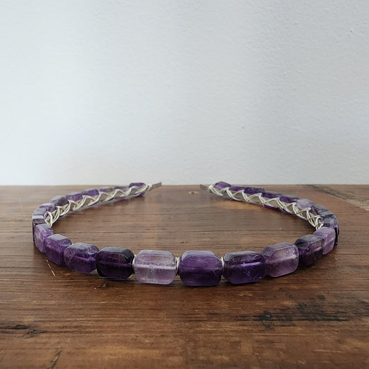 A purple amethyst headband with wire wrapped gemstones displayed on a wooden surface.